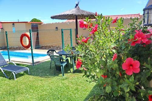 einen Hinterhof mit einem Pool, einem Tisch, Stühlen und Blumen in der Unterkunft Bungalow Curro Pareja 97 in Conil de la Frontera