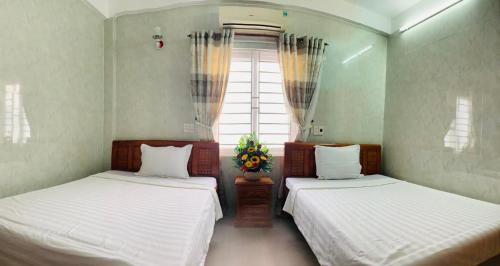 two beds in a room with a window at HAI DANG HOTEL in Xóm Ðé
