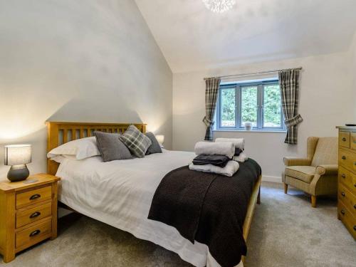 a bedroom with a bed and a chair and a window at Rinstone Lodge, Thornton-Le-Dale. Moors cottage with hot tub in Thornton Dale