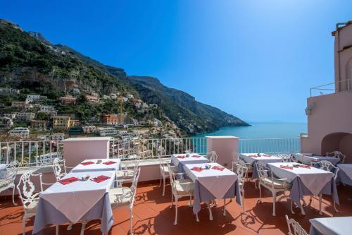 a balcony with tables and chairs with a view of the ocean at Hotel Casa Albertina in Positano