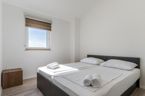 a white bedroom with a large bed with towels on it at Breakaway Apartment in Cres