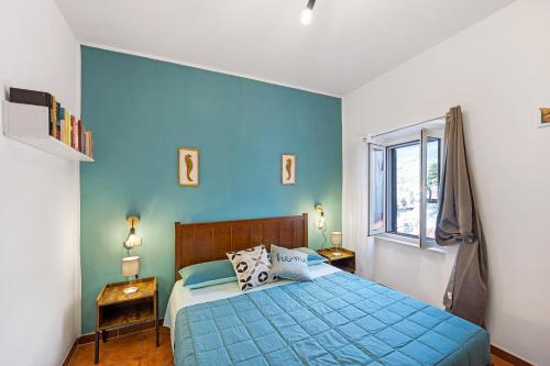 Dormitorio azul con cama y ventana en Domus Regina Elena en San Remo
