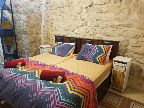 a bedroom with two beds with colorful sheets and pillows at אורות בעתיקה - צימרים ונופש בצפת in Safed