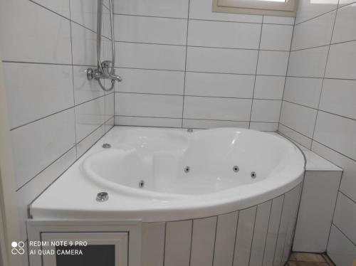a white bath tub in a white tiled bathroom at On the edge of the river על קצה הנחל in Mas'ade