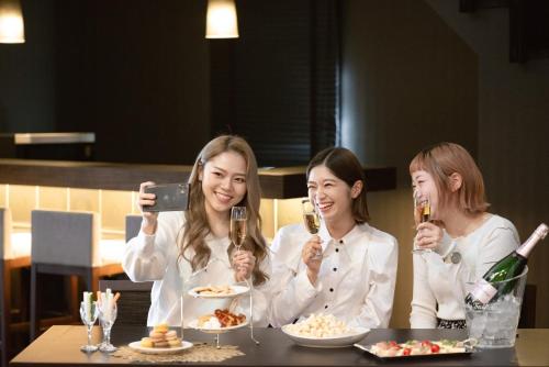 Tres mujeres sentadas en una mesa bebiendo champán. en Maebashi - House - Vacation STAY 64426v, en Maebashi