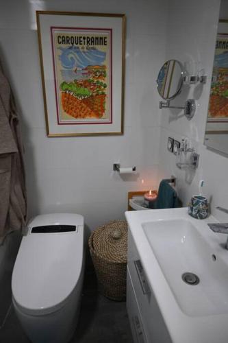 une salle de bain avec des toilettes blanches et un lavabo dans l'établissement appartement carqueiranne le port, à Carqueiranne
