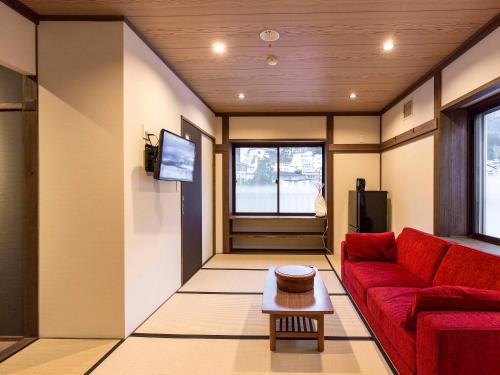 a living room with a red couch and a tv at Shirakaba in Nozawa Onsen