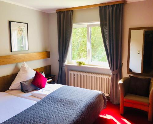 1 dormitorio con cama, ventana y silla en Hotel-Restaurant Berghof, en Johannesberg