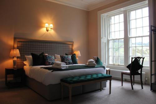 a bedroom with a bed with a green bench and windows at Lochieheads House in Cupar