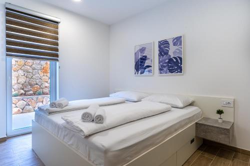 a white bedroom with a bed with towels on it at Apartment Blue Monstéra in Cres