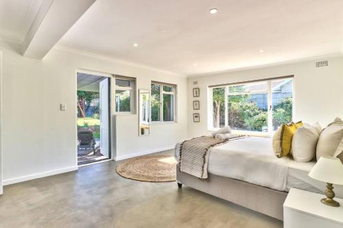 a white bedroom with a large bed and windows at Family Home, WiFi, Patio, Secure Parking in Cape Town
