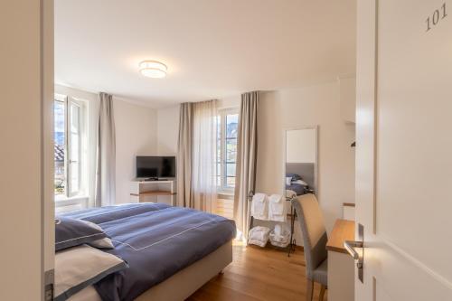 um quarto com uma cama, uma secretária e uma televisão em Verena's Boutique Villa au lac em Sachseln