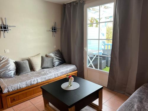 ein Wohnzimmer mit einem Sofa, einem Tisch und einem Fenster in der Unterkunft La Résidence Vacances Mondésir appartement 3 étoiles in Monflanquin