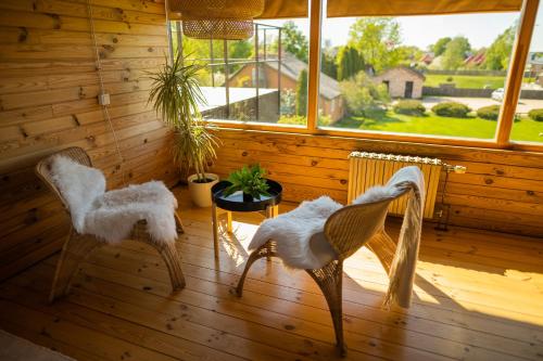 two chairs and a table in a room with a window at Vēju Paradīze in Pāvilosta