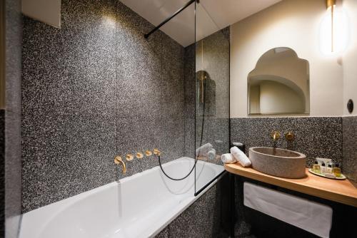 a bathroom with a tub, sink, and mirror at Hôtel de l'Abbaye - Lyon in Lyon
