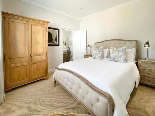 una camera con un grande letto e un armadio in legno di Petit Ermitage a Franschhoek