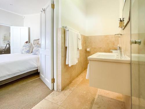 a bathroom with a bed and a sink and a mirror at Petit Ermitage in Franschhoek