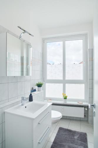a white bathroom with a sink and a window at Ferienwohnung Hafenbucht Moba-Travel in Travemünde