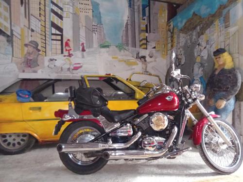 a red motorcycle parked next to a yellow car at Appartement le labyrinthe du peintre in Bransat