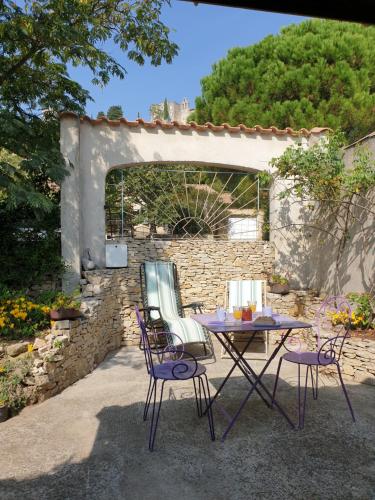 a patio with a table and chairs and a stone wall at Pause couleur Lavandula in Roussas