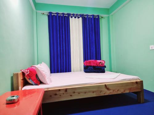 a room with a bed with a blue curtain at Neoravalley Homestay, Lava in Rishop