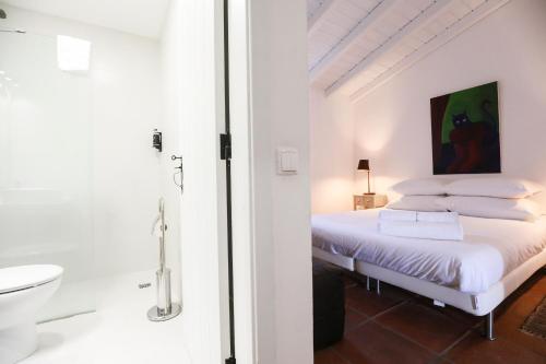 a white bedroom with a bed and a bathroom at Quinta da Tapada de São Pedro in Vimieiro