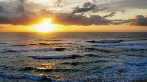two waves in the ocean with the sunset in the background at Kaia Homestead in Sodwana Bay