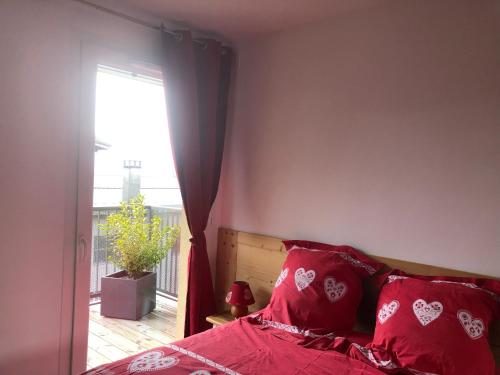 um quarto com uma cama com almofadas vermelhas e uma janela em Charmant appartement em Saint-Gervais-les-Bains