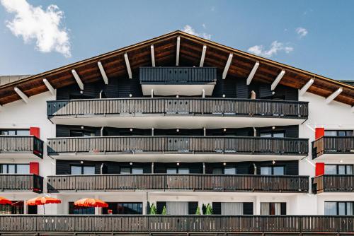 un edificio de apartamentos con balcones y sombrillas de color naranja en Experimental Chalet, en Verbier