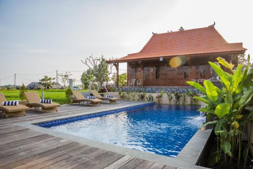 a swimming pool with lounge chairs and a house at Victory Munggu in Canggu