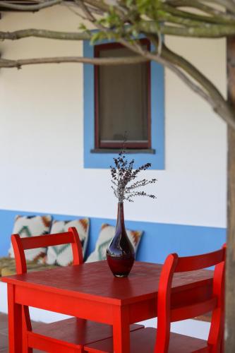 a red table with a vase on top of it at Quinta da Tapada de São Pedro in Vimieiro