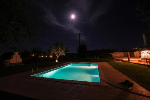 a swimming pool at night with the moon in the background at Quinta da Tapada de São Pedro in Vimieiro