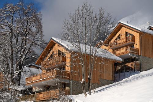 a large wooden building in the snow at Le refuge des Sens Chalet Harmonie in Vaujany
