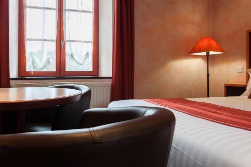 a hotel room with a bed and a table and chair at La Couronne in Jougne
