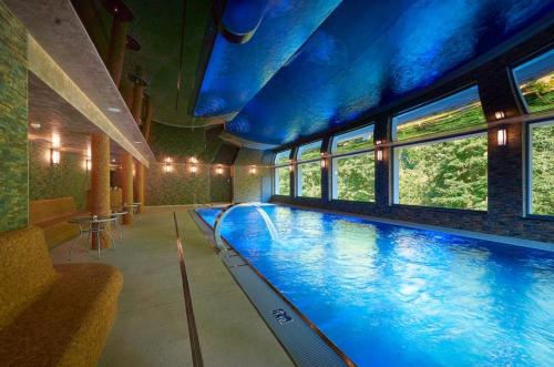 a large swimming pool in a building with windows at Wellness Hotel GREEN PARADISE in Pirkenhammer