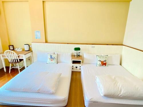 two twin beds in a room with a table and a chair at Village Villa B&B in Zhuqi