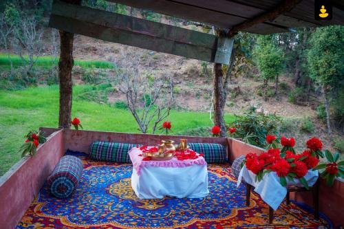 un patio con una mesa con flores rojas. en LivingStone Shimla Jungle Stay, en Shimla