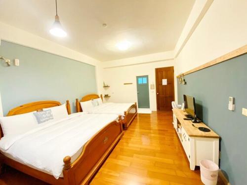 a bedroom with two beds and a television in it at Village Villa B&B in Zhuqi