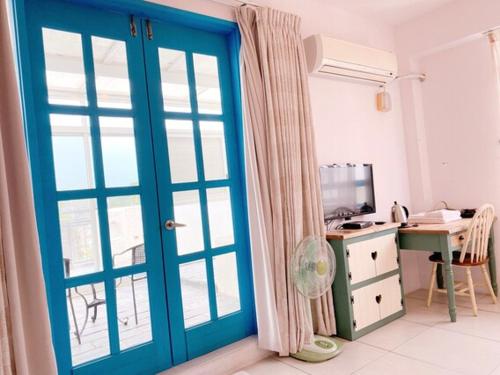 a room with a blue door and a desk with a computer at Village Villa B&B in Zhuqi