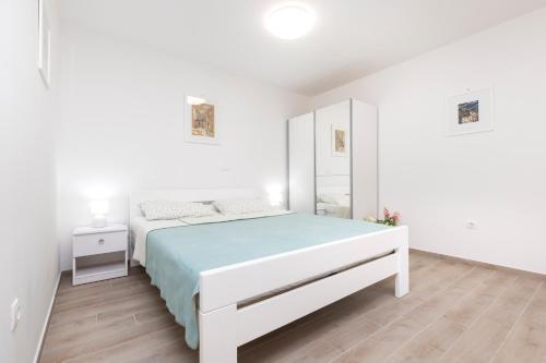 a white bedroom with a bed and a mirror at Apartment Morris in Veli Lošinj