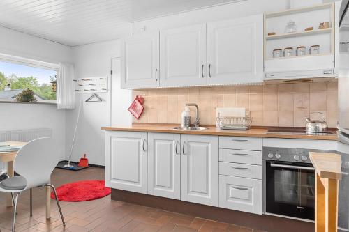 a kitchen with white cabinets and a red rug at Private fully functional apartment in a villa near forrest in Sønderborg