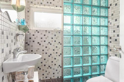 een badkamer met blauwe betegelde muren en een wastafel bij Private fully functional apartment in a villa near forrest in Sønderborg