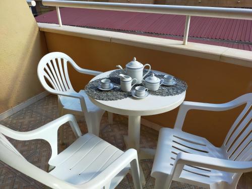 einen Tisch mit drei Stühlen und ein Tee-Set darauf in der Unterkunft ACV - Isla Park-1ª Linea Planta 1 Sur in Oropesa del Mar