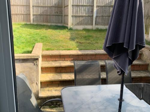 an umbrella sitting on top of a table in a backyard at Kirkby House, 3 bedroom, sleeps up to 7 with sofa bed, holiday, corporate, contractor stays in Kirkby in Ashfield