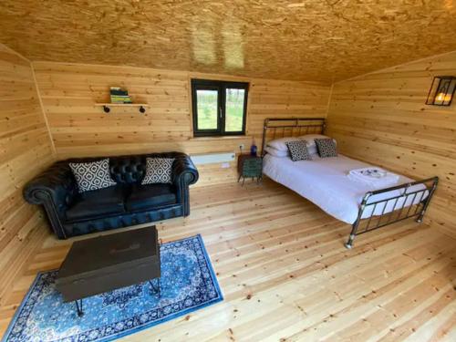 Habitación con cama y sofá en una cabaña de madera. en Lakeside Lodge en Taunton