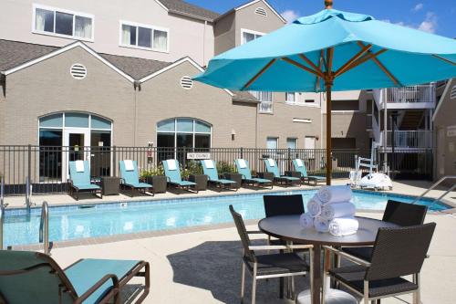 un tavolo con ombrellone blu accanto a una piscina di Sonesta ES Suites Detroit Warren a Warren