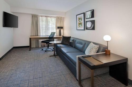 a living room with a blue couch and a desk at Sonesta ES Suites Atlanta Kennesaw Town Center in Kennesaw