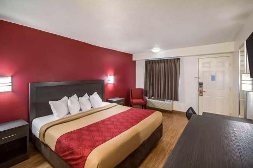 a hotel room with a bed and a red wall at Days Inn by Wyndham Charleston WV in Charleston