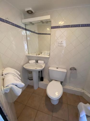 a white bathroom with a toilet and a sink at Hôtel Belle Vue d'Angleterre in Le Grau-du-Roi