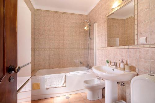 een badkamer met een bad, een wastafel en een toilet bij Villa Fernando in Quarteira